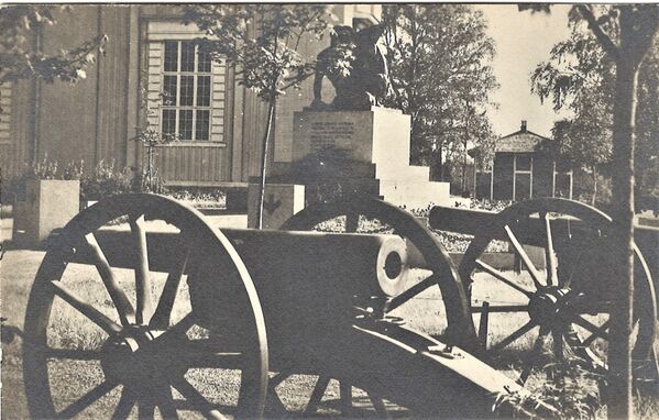 Lapua sankaripatsas 1918 ja tykit
Kirkon vieressÃ¤, kuvassa myÃ¶s tykit. Lapuan suojeluskunta lahjoitti vuonna 1921 Lapuan seurakunnalle kaksi kenttÃ¤tykkiÃ¤. Toinen oli vallattu Pekkalan taistelussa RuovedellÃ¤ 13.2.1918 ja toinen EvÃ¤jÃ¤rven taistelussa LÃ¤ngelmÃ¤ellÃ¤ 12.3.1918. Tykit sijoitettiin vapaussodan muistopatsaan edustalle niin, ettÃ¤ kulkureitti patsaalle meni tykkien vÃ¤listÃ¤. Sittemmin tykit siirrettiin hieman kauemmas kirkkomaan kulmaukseen, mutta yhÃ¤ patsaan yhteyteen. NÃ¤in kertoo Helemi. Kortti on J SyvÃ¤ojan tuotantoa. Ei ole kulkenut postissa.
